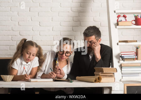 Back to school and home schooling. School time of girl sisters with father. Education and knowledge day. Father helps children to study at home. Teach Stock Photo