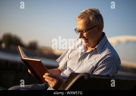 Outdoor portrait of senior man who is reading book. Stock Photo