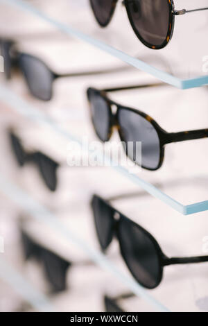 Fashionable sunglasses on a shelf in optical store