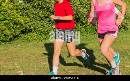 Teenage girls are training together on grass in a park with trees and bushes in the background. Stock Photo