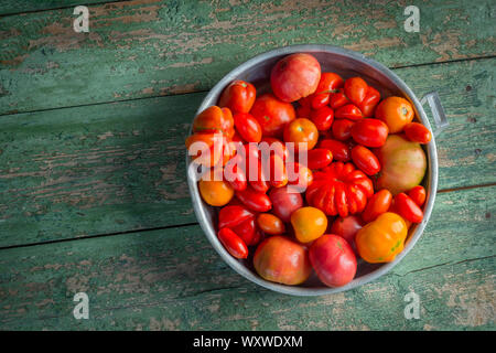 Fresh colorful ripe Fall heirloom tomatoes in basket over wooden background, top view, horizontal composition Stock Photo
