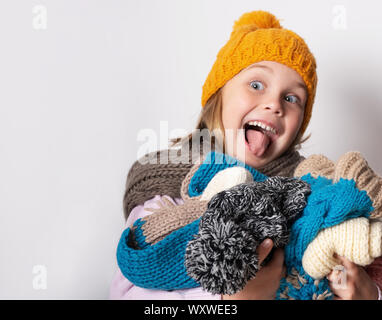 little girl wearing knitted hat, scarf and sweater, holding a pile of hats, Stock Photo