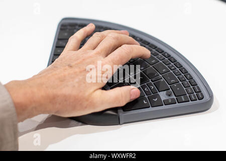 Duesseldorf, Germany. 18th Sep, 2019. A woman types 'TiPY' with one hand using the PC keyboard. The keyboard is designed to be operated with only one hand. The fair presents possibilities to lead a largely self-determined life despite disability with the help of innovative rehabilitation technology. Around 700 exhibitors from over 40 countries will be taking part. Credit: Marcel Kusch/dpa/Alamy Live News Stock Photo