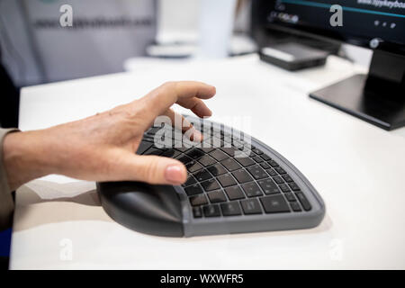 Duesseldorf, Germany. 18th Sep, 2019. A woman types 'TiPY' with one hand using the PC keyboard. The keyboard is designed to be operated with only one hand. The fair presents possibilities to lead a largely self-determined life despite disability with the help of innovative rehabilitation technology. Around 700 exhibitors from over 40 countries will be taking part. Credit: Marcel Kusch/dpa/Alamy Live News Stock Photo