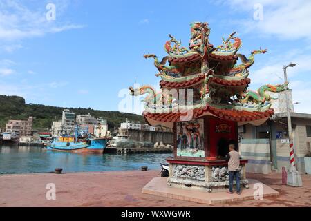 YEHLIU, TAIWAN - NOVEMBER 24, 2018: Person visits a shrine next to the harbor of Yehliu, Taiwan. Yehliu is a popular tourism destination. Stock Photo