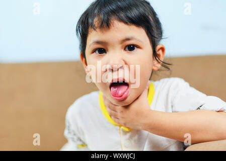 Coughing and Sore throat / Asian little girl sick fever cold , Child Stick out tongue Stock Photo
