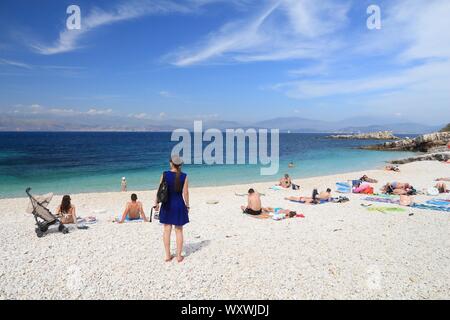 CORFU, GREECE - MAY 31, 2016: People enjoy the beach in Kassiopi, Corfu Island, Greece. 558,000 tourists visited Corfu in 2012. Stock Photo