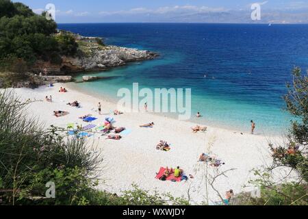 CORFU, GREECE - MAY 31, 2016: People enjoy the beach in Kassiopi, Corfu Island, Greece. 558,000 tourists visited Corfu in 2012. Stock Photo