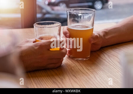 Two man's hands holding beer glasses or clinking in the pub Stock Photo