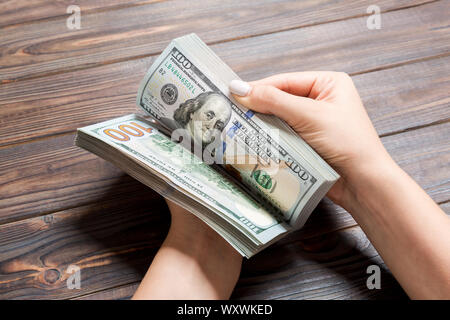 Businesswoman's hands counting one hundred dollar bills on wooden background. Salary and wage concept. Perspective view of Investment concept. Stock Photo