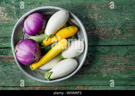 Fresh eggplants and zucchini in basket over wooden green background. Flat lay. Healthy food or diet. Stock Photo