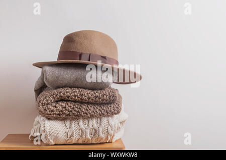 Pile of warm knitted woolen winter sweates and felt hat Stock Photo