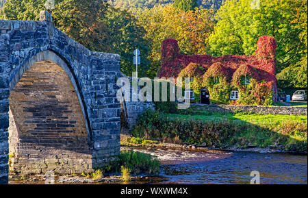 A sign post on the narrow bridge beside the Tu Hwnt l'r Bont Tearoom on the banks of the River Conwy in Llanrwst, north Wales. One of the UK's most scenic views has been ruined with the installation of a new road sign warning drivers to give way across a narrow bridge. Stock Photo