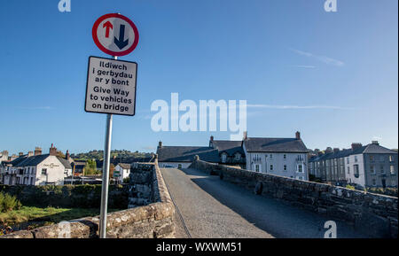 A sign post on the narrow bridge beside the Tu Hwnt l'r Bont Tearoom on the banks of the River Conwy in Llanrwst, north Wales. One of the UK's most scenic views has been ruined with the installation of a new road sign warning drivers to give way across a narrow bridge. Stock Photo