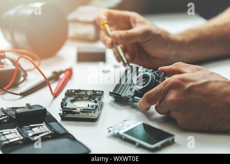 electronic repair service - technician repairing digital camera in office Stock Photo