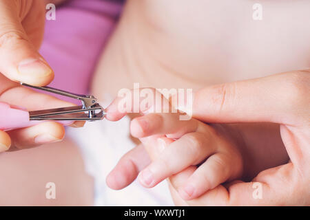 nail and finger manicure for baby by hand mom hold small scissor to cut nail for clean with love and care. Stock Photo