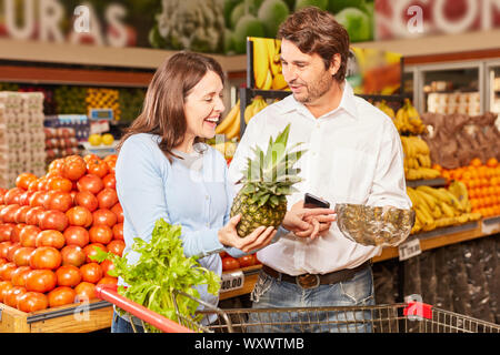 Couple shopping at the supermarket uses smartphone app for product comparison Stock Photo