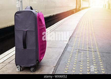 Suitcase standing on the train platform Stock Photo