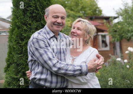 Cheerful mature couple resting in green summer garden smiling. Stock Photo