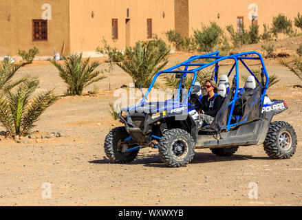 Itrane, Morocco - Feb 24, 2016: blue Polaris RZR 800 with woman pilot in a small Berber village in Morocco desert near Merzouga Stock Photo