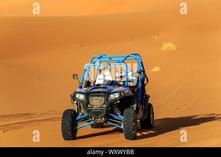 Merzouga, Morocco - Feb 22, 2016: Blue Polaris RZR 800 and pilot in Morocco desert near Merzouga. Merzouga is a small village located in the Saharan s Stock Photo