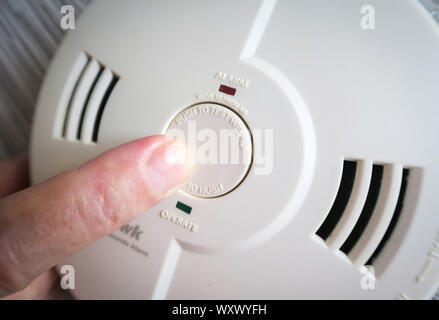 Man Posing the Test Button on an in-home smoke detector, USA Stock Photo