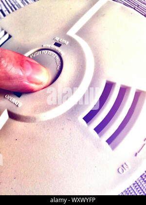 Man Posing the Test Button on an in-home smoke detector, USA Stock Photo