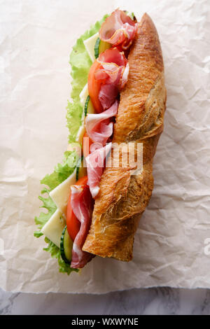 https://l450v.alamy.com/450v/wxwyne/fresh-baguette-sandwich-bahn-mi-styled-ham-sliced-cheese-tomatoes-and-fresh-lettuce-in-wrapping-paper-on-white-marble-background-wxwyne.jpg