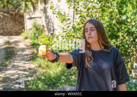 Cukuroren, Bilecik / Turkey -September 08 2019: Portrait of a girl holding at a half eaten apple and green tree in background Stock Photo