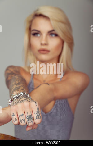 Woman with tattoos on her fingers holding her hand towards camera. Stock Photo