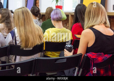 People in auditory during presentation or seminar. Teenagers or young women at university lecture or seminar. Back side view with no faces Stock Photo