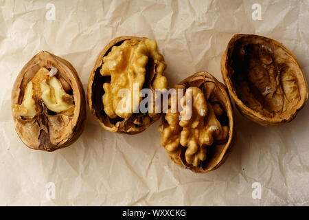 Raw walnuts in cracked nutshells on parchment paper. Overhead view Stock Photo