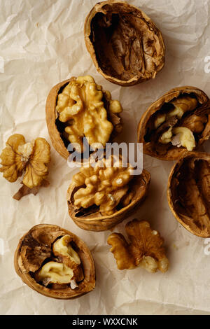 Raw walnuts in cracked nutshells on parchment paper. Overhead view Stock Photo