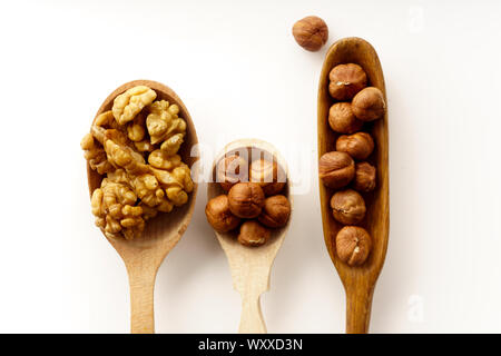Walnuts and hazelnuts in wooden spoons isolated on white background. Top view Stock Photo