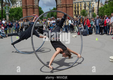 Barcelona, Catalonia/Spain - 1st May 2017: Tourists watching Street performers with circus hoops in front of the Arc de Triomf in Barcelona Stock Photo