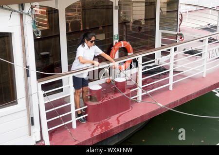 Paris, France - Aug 31, 2019: Female sailor undocking a tourboat on the Seine River in Paris, France. Stock Photo