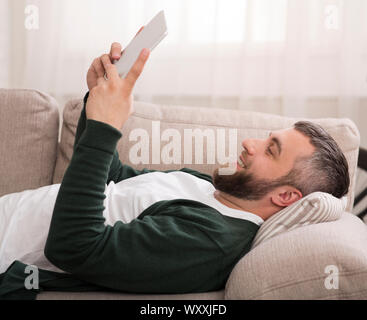 Lazy man using digital tablet at home Stock Photo