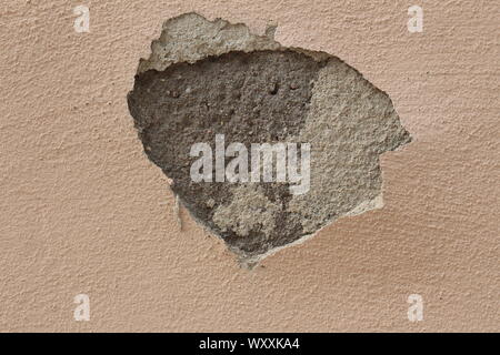 Wall with a big hole where the plaster has fallen off, leaving a view beneath it Stock Photo