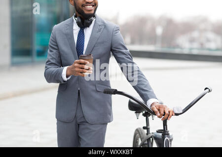 Businessman coming to work by bike and drinking coffee outdoors Stock Photo