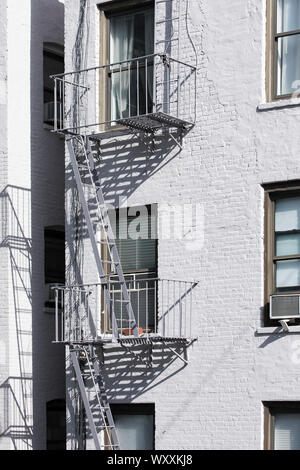 Traditional typical metal fire escape ladder on walk-up brownstone apartment block on west side Manhattan, New York City Stock Photo