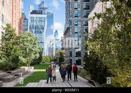 Tourists and disused train tracks on The High Line elevated park walkway and high rise skyscrapers on west side Manhattan, New York City Stock Photo