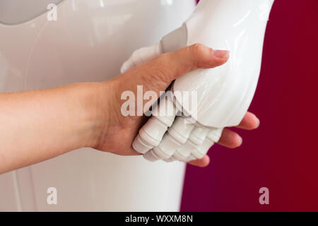 A woman shaking hands with a robot Stock Photo