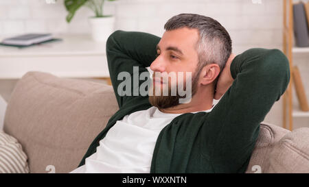 Attractive pensive man laying on couch at home Stock Photo