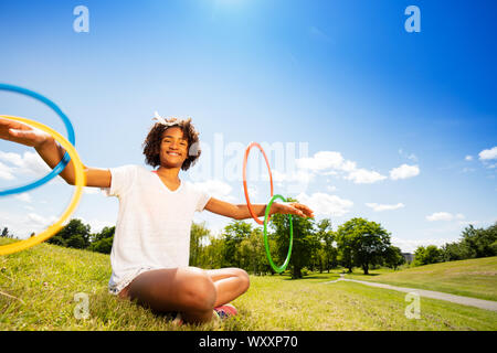 Portrait of a cute young girl with curly hair in park rotate hoops on her hands Stock Photo
