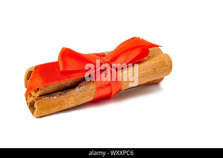 Cinnamon tied with a red ribbon, closeup on a white background. Stock Photo