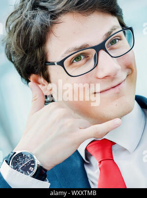 young businessman gesturing call phone and making 'call me' or 'on the phone' gesture outside of his office Stock Photo