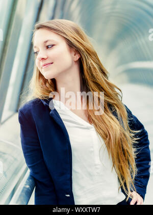 Beautiful young woman with long blond hair leaning on railing at bridge Stock Photo