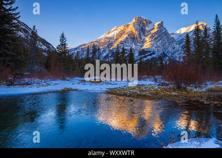 Mount Kidd, a mountain in Kananaskis in the Canadian Rocky Mountains, Alberta, Canada and the Kananaskis River in winter Stock Photo