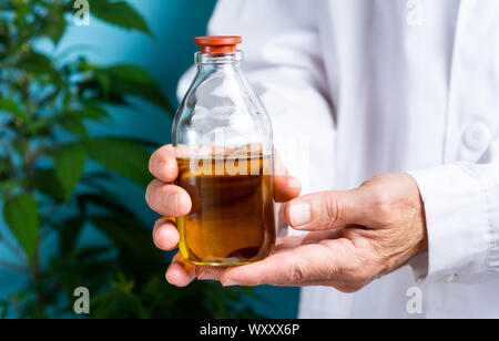 Scientist holding cannabis oil close up, alternative medicine abstract Stock Photo