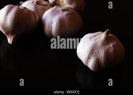 Garlic bulbs against plain black background Stock Photo